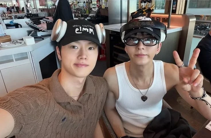 Cassius and Natha wearing caps at a cafe with a peace sign